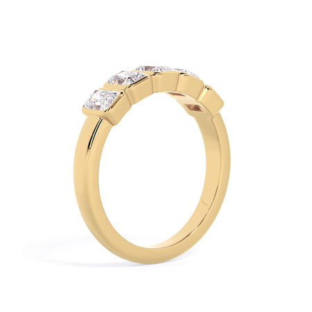A picture of a five stone diamond wedding ring with radiant cut diamonds that are bezel set in yellow gold on a white background with a slightly angled, through the finger view.