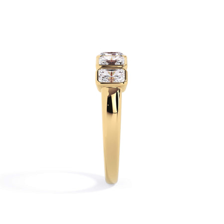 A picture of a five stone diamond wedding ring with radiant cut diamonds that are bezel set in yellow gold on a white background with a side profile view.