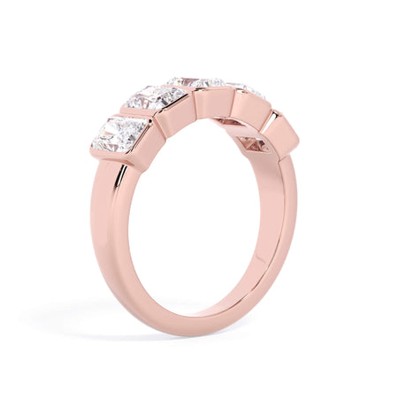 A picture of a five stone diamond wedding ring with radiant cut diamonds that are bezel set in rose gold on a white background with a slightly angled, through the finger view.