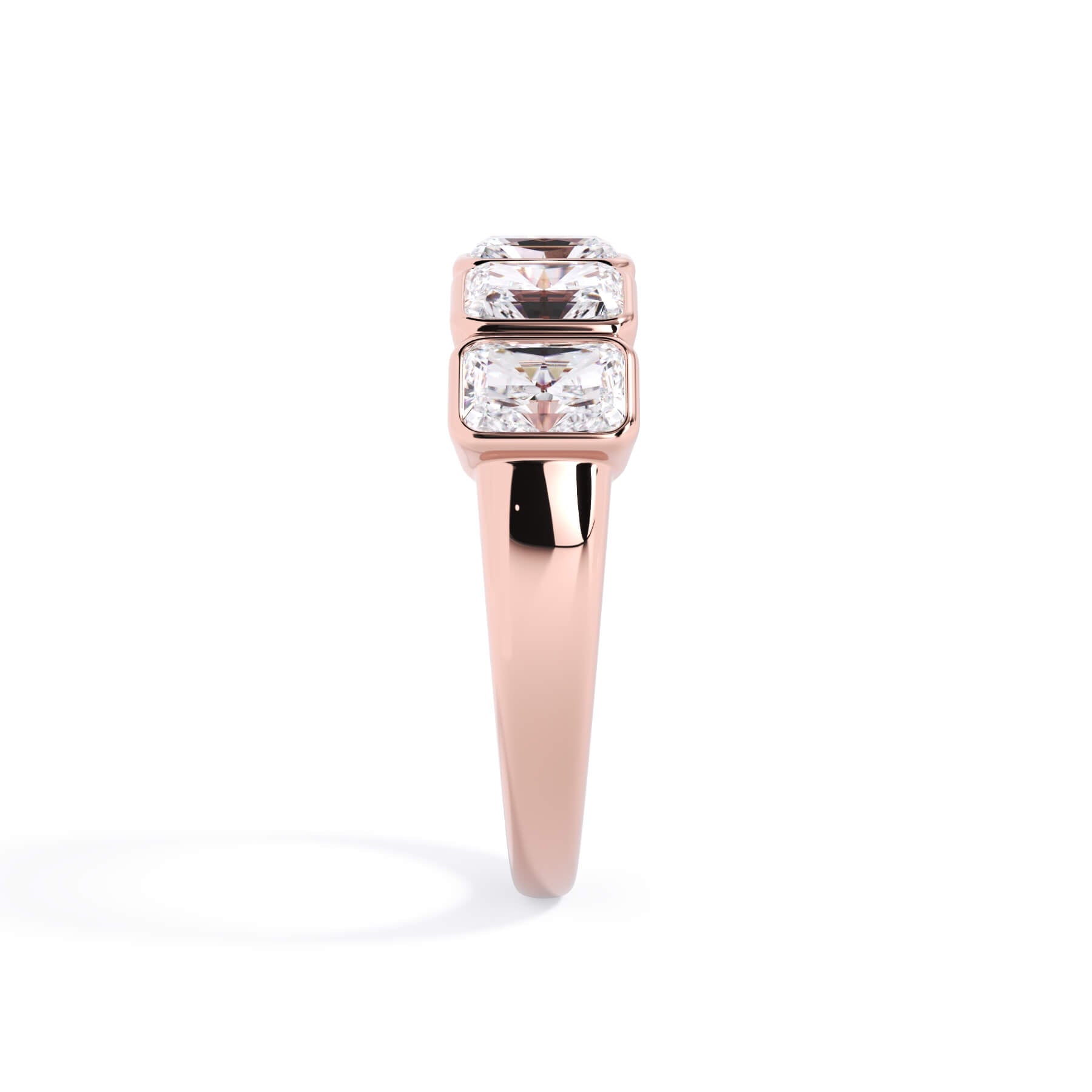 A picture of a five stone diamond wedding ring with radiant cut diamonds that are bezel set in rose gold on a white background with a side profile view.