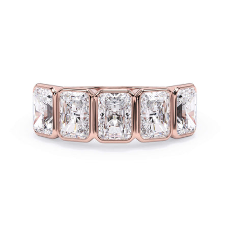 A picture of a five stone diamond wedding ring with radiant cut diamonds that are bezel set in rose gold on a white background with the ring facing forward, lying down.