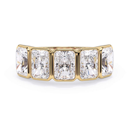 A picture of a five stone diamond wedding ring with radiant cut diamonds that are bezel set in yellow gold on a white background with the ring facing forward, lying down.