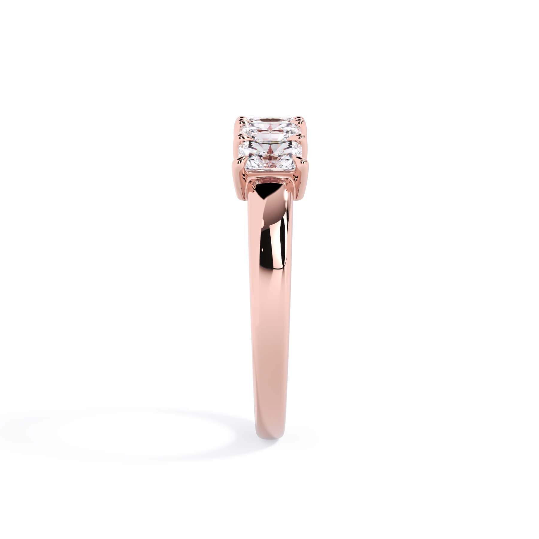A picture of a five stone diamond wedding ring with radiant cut diamonds that are shared prong set in rose gold on a white background with a side profile view.