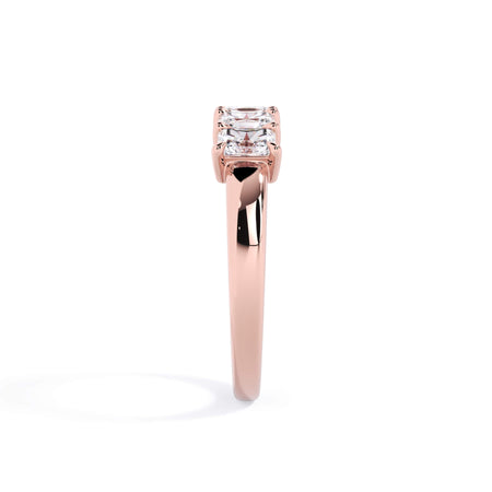 A picture of a five stone diamond wedding ring with radiant cut diamonds that are shared prong set in rose gold on a white background with a side profile view.