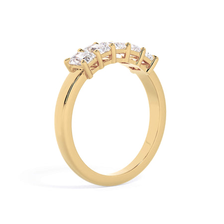 A picture of a five stone diamond wedding ring with radiant cut diamonds that are shared prong set in yellow gold on a white background with a slightly angled, through the finger view.