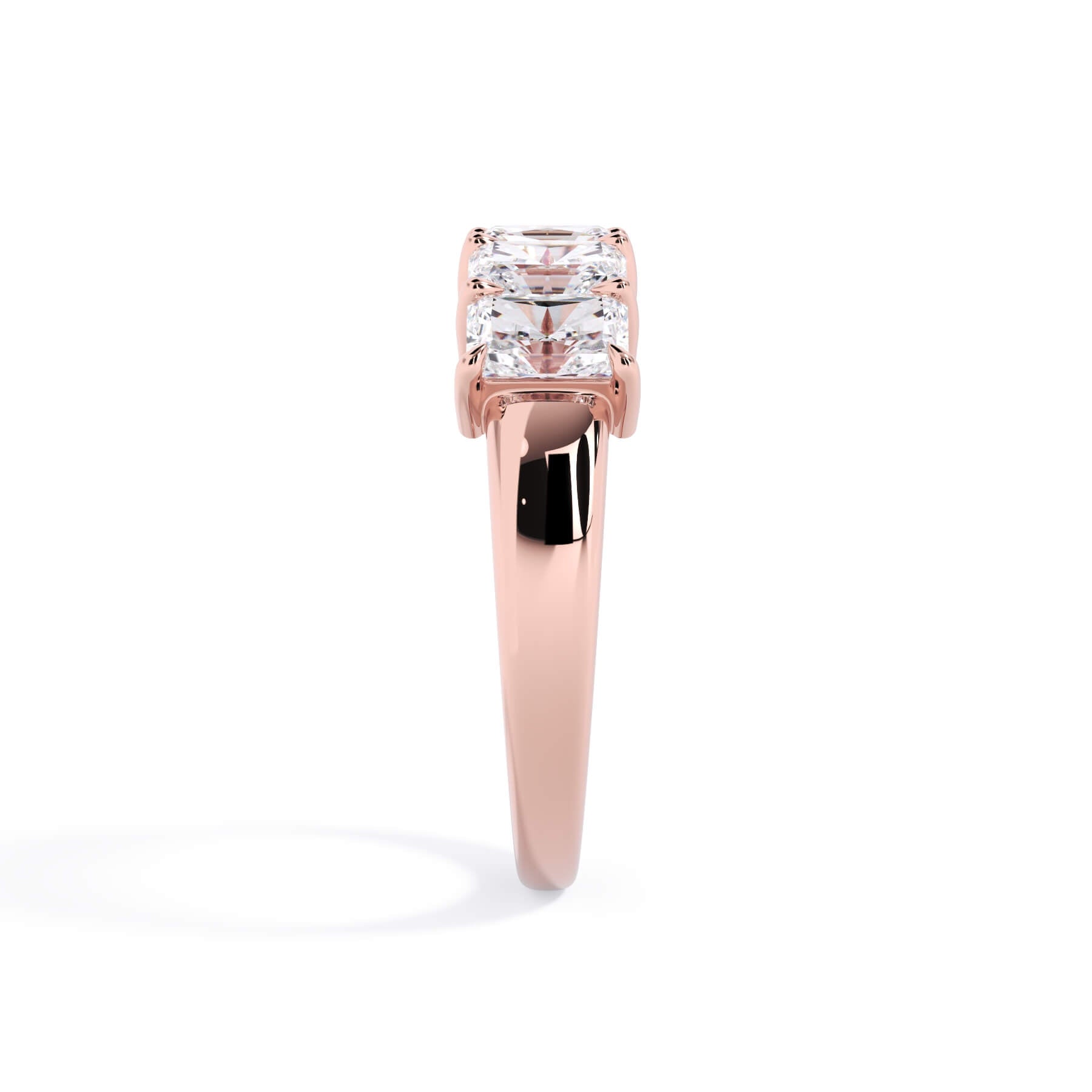 A picture of a five stone diamond wedding ring with radiant cut diamonds that are shared prong set in rose gold on a white background with a side profile view.
