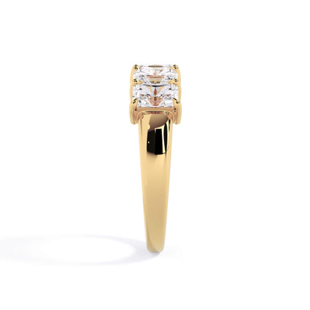 A picture of a five stone diamond wedding ring with radiant cut diamonds that are shared prong set in yellow gold on a white background with a side profile view.