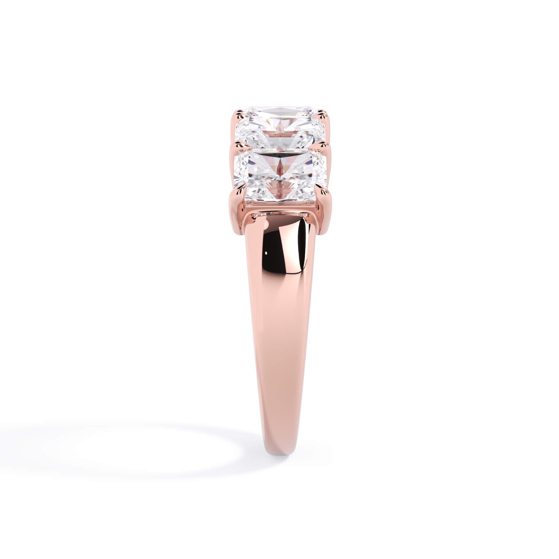 A picture of a five stone diamond wedding ring with radiant cut diamonds that are shared prong set in rose gold on a white background with a side profile view.
