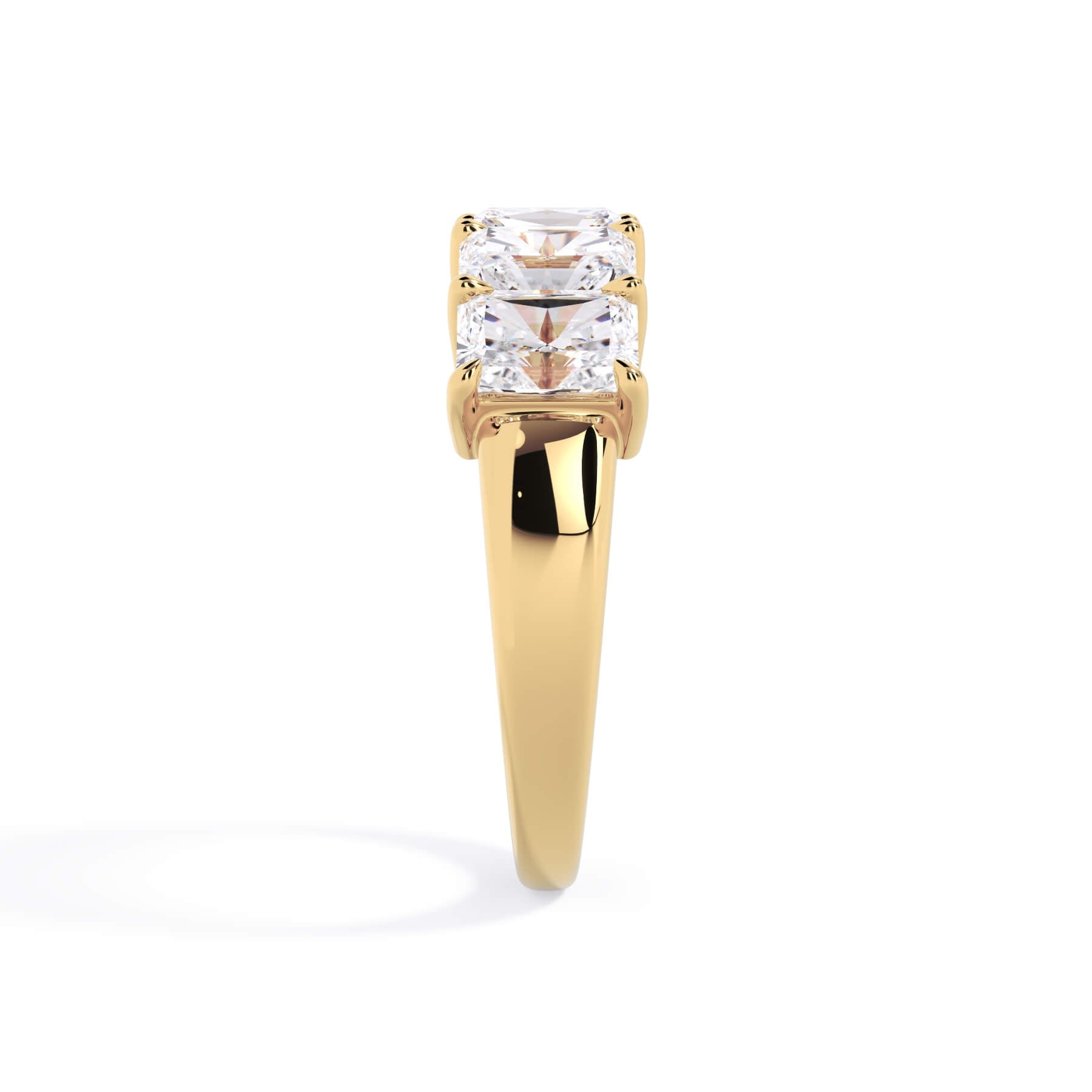 A picture of a five stone diamond wedding ring with radiant cut diamonds that are shared prong set in yellow gold on a white background with a side profile view.