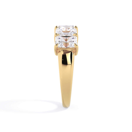 A picture of a five stone diamond wedding ring with radiant cut diamonds that are shared prong set in yellow gold on a white background with a side profile view.