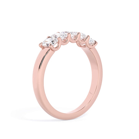 A picture of a five stone diamond wedding ring with radiant cut diamonds that are u prong set in rose gold on a white background with a slightly angled, through the finger view.