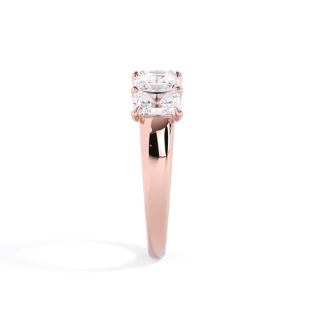 A picture of a five stone diamond wedding ring with radiant cut diamonds that are u prong set in rose gold on a white background with a side profile view.