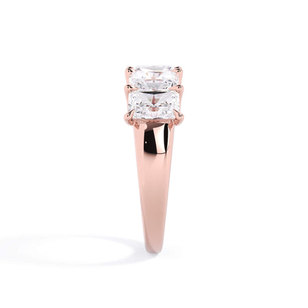A picture of a five stone diamond wedding ring with radiant cut diamonds that are u prong set in rose gold on a white background with a side profile view.