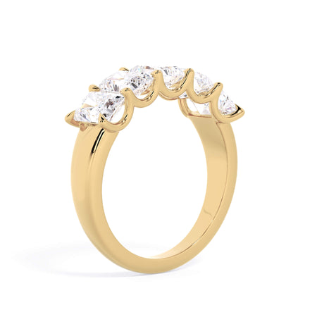 A picture of a five stone diamond wedding ring with radiant cut diamonds that are u prong set in yellow gold on a white background with a slightly angled, through the finger view.
