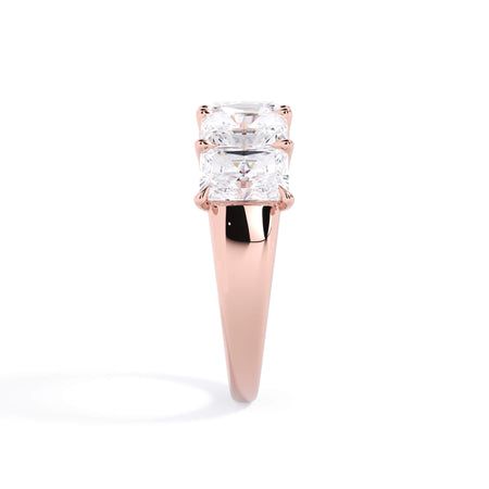 A picture of a five stone diamond wedding ring with radiant cut diamonds that are u prong set in rose gold on a white background with a side profile view.
