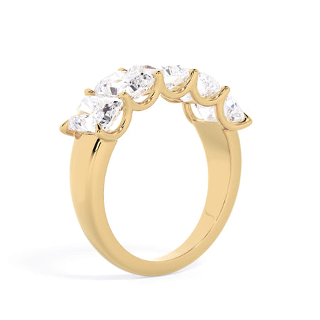 A picture of a five stone diamond wedding ring with radiant cut diamonds that are u prong set in yellow gold on a white background with a slightly angled, through the finger view.