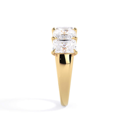 A picture of a five stone diamond wedding ring with radiant cut diamonds that are u prong set in yellow gold on a white background with a side profile view.