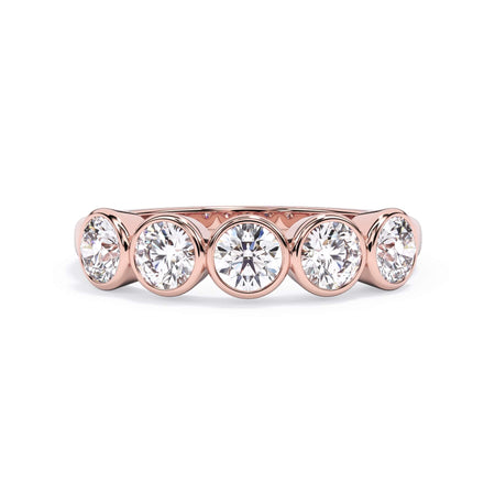 A picture of a five stone diamond wedding ring with round diamonds that are bezel set in rose gold on a white background with the ring facing forward, lying down.
