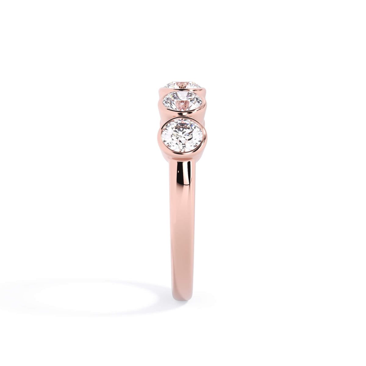 A picture of a five stone diamond wedding ring with round diamonds that are bezel set in rose gold on a white background with a side profile view.
