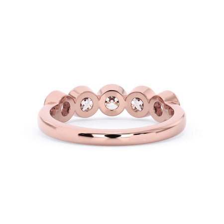 A picture of a five stone diamond wedding ring with round diamonds that are bezel set in rose gold on a white background with a view of the underside of the ring.