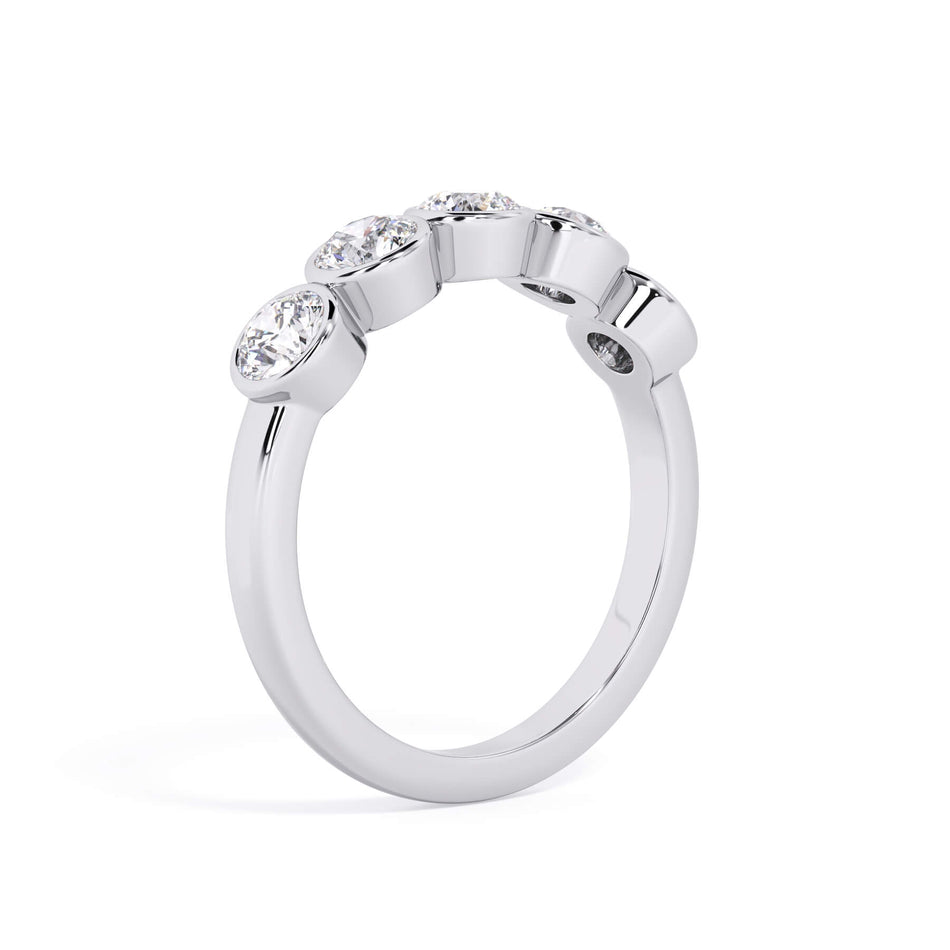 A picture of a five stone diamond wedding ring with round diamonds that are bezel set in white gold or platinum on a white background with a slightly angled, through the finger view.