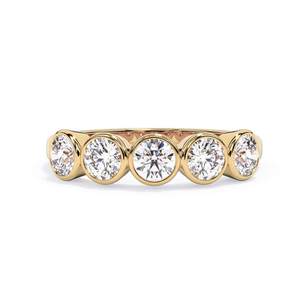 A picture of a five stone diamond wedding ring with round diamonds that are bezel set in yellow gold on a white background with the ring facing forward, lying down.