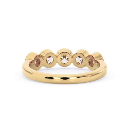 A picture of a five stone diamond wedding ring with round diamonds that are bezel set in yellow gold on a white background with a view of the underside of the ring.