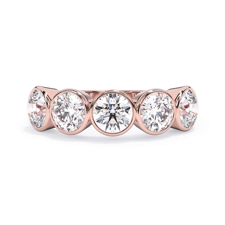 A picture of a five stone diamond wedding ring with round diamonds that are bezel set in rose gold on a white background with the ring facing forward, lying down.