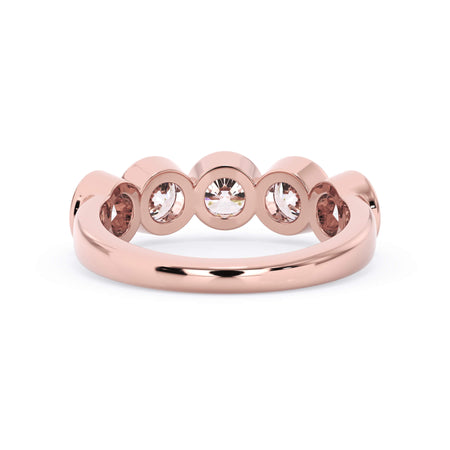 A picture of a five stone diamond wedding ring with round diamonds that are bezel set in rose gold on a white background with a view of the underside of the ring.