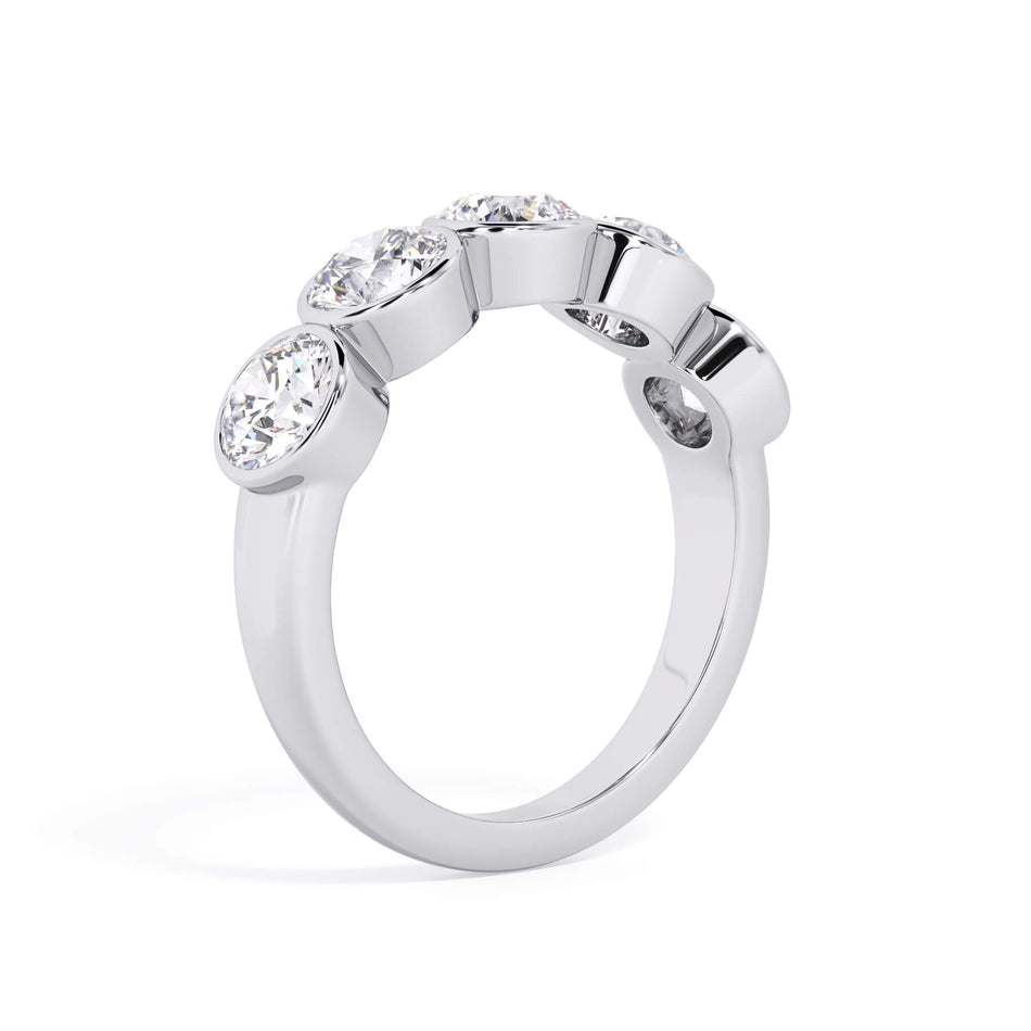 A picture of a five stone diamond wedding ring with round diamonds that are bezel set in white gold or platinum on a white background with a slightly angled, through the finger view.