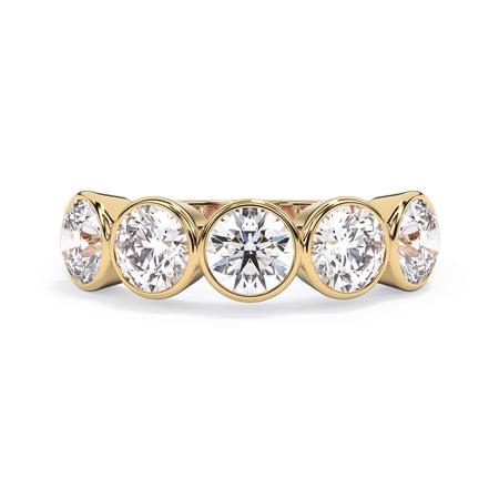 A picture of a five stone diamond wedding ring with round diamonds that are bezel set in yellow gold on a white background with the ring facing forward, lying down.