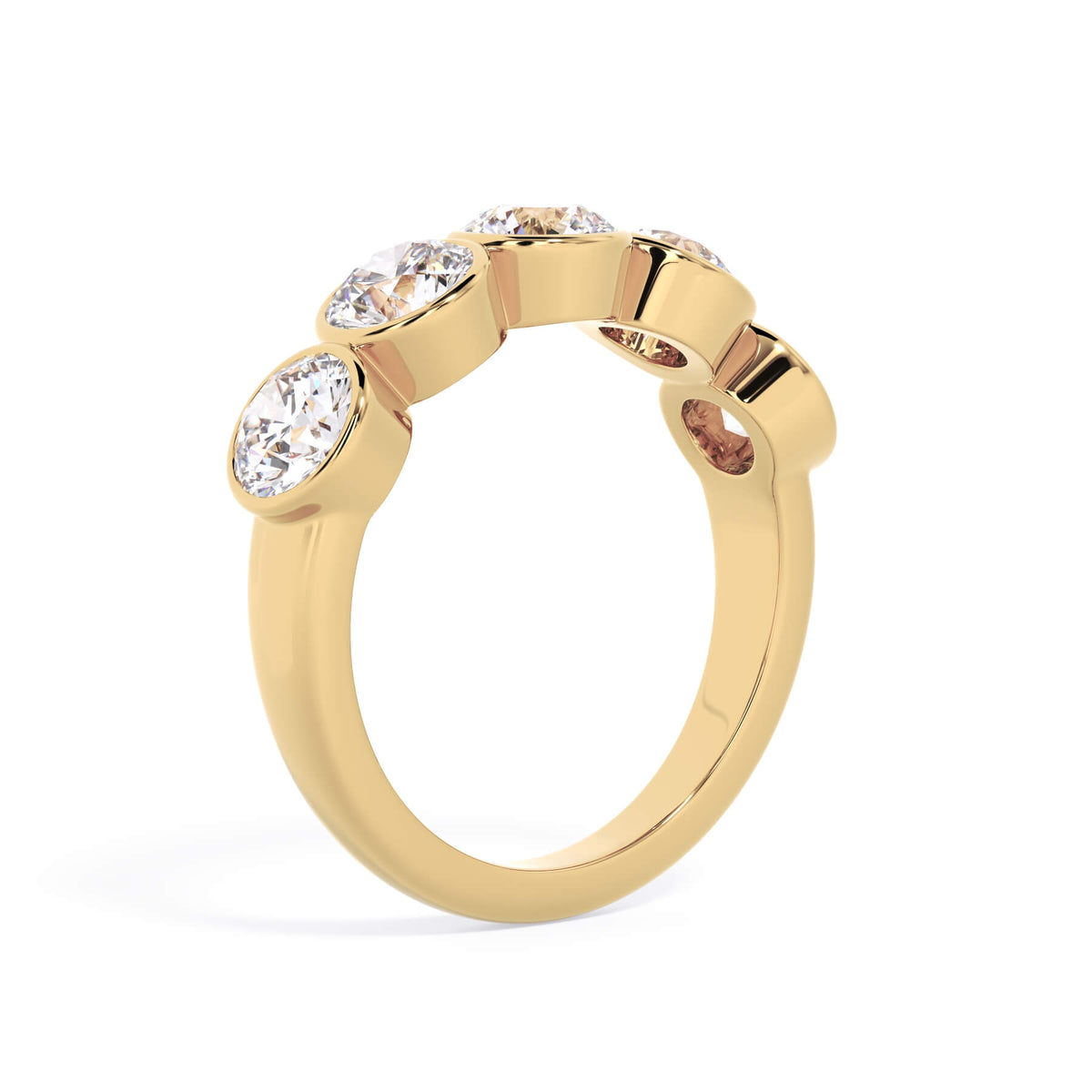 A picture of a five stone diamond wedding ring with round diamonds that are bezel set in yellow gold on a white background with a slightly angled, through the finger view.
