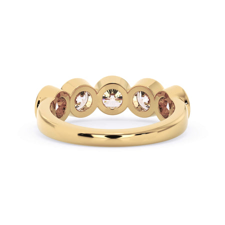 A picture of a five stone diamond wedding ring with round diamonds that are bezel set in yellow gold on a white background with a view of the underside of the ring.