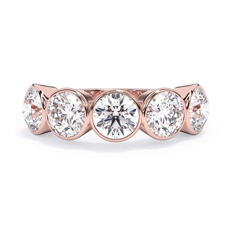 A picture of a five stone diamond wedding ring with round diamonds that are bezel set in rose gold on a white background with the ring facing forward, lying down.