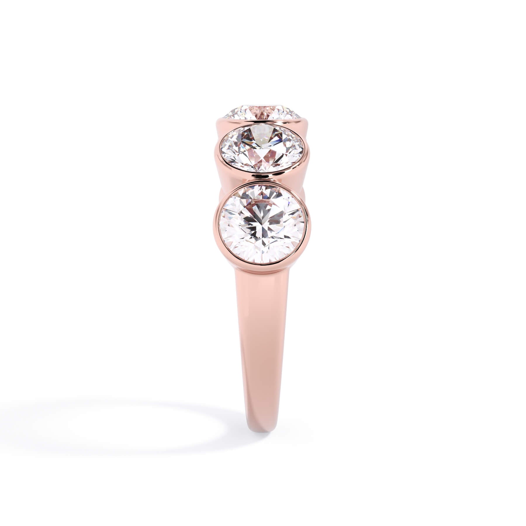 A picture of a five stone diamond wedding ring with round diamonds that are bezel set in rose gold on a white background with a side profile view.