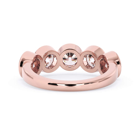 A picture of a five stone diamond wedding ring with round diamonds that are bezel set in rose gold on a white background with a view of the underside of the ring.