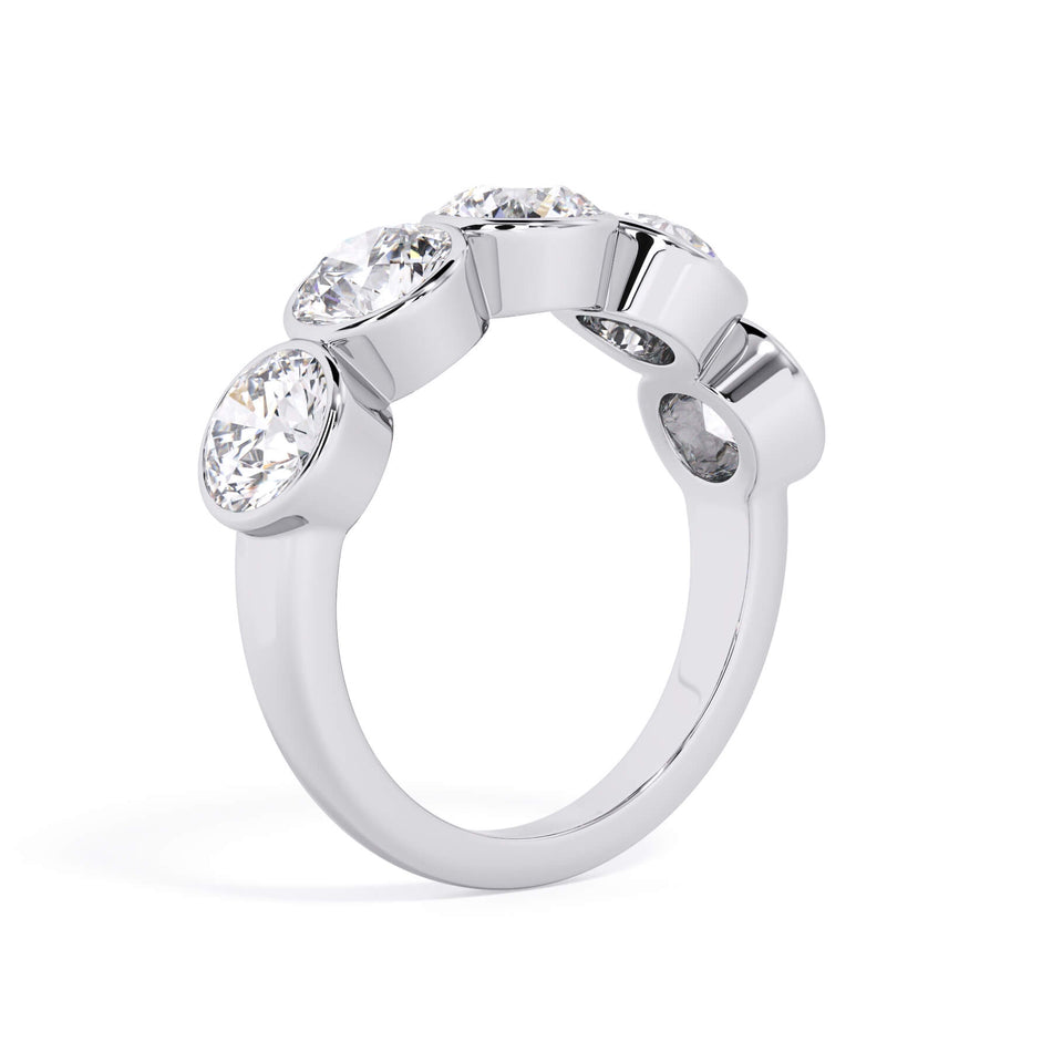 A picture of a five stone diamond wedding ring with round diamonds that are bezel set in white gold or platinum on a white background with a slightly angled, through the finger view.