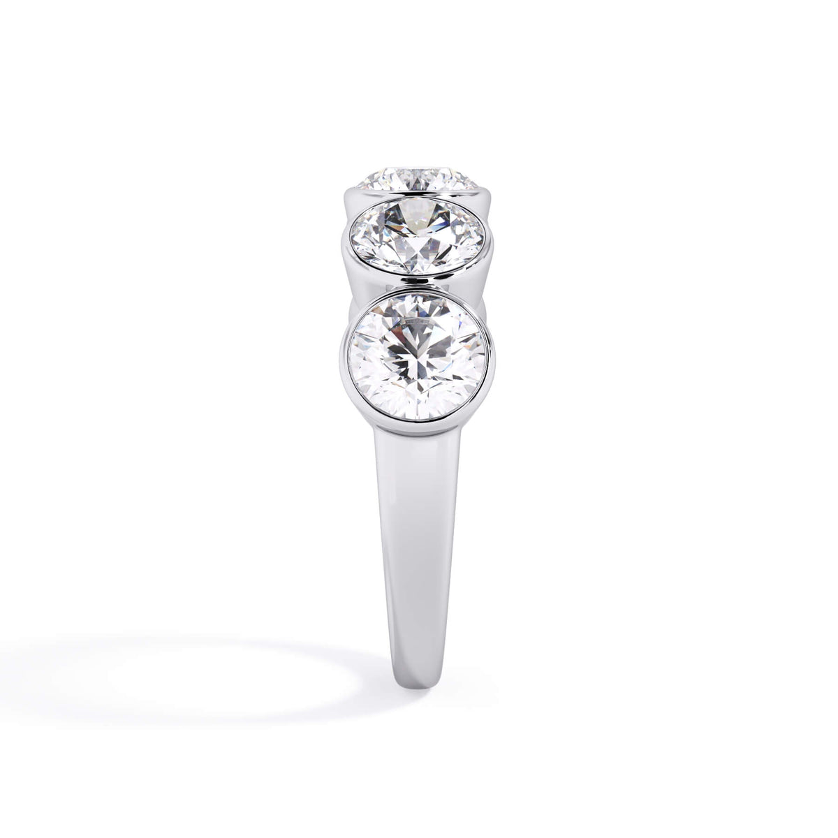 A picture of a five stone diamond wedding ring with round diamonds that are bezel set in white gold or platinum on a white background with a side profile view.