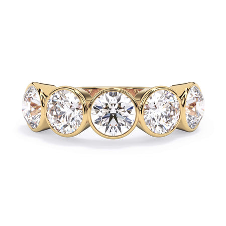 A picture of a five stone diamond wedding ring with round diamonds that are bezel set in yellow gold on a white background with the ring facing forward, lying down.