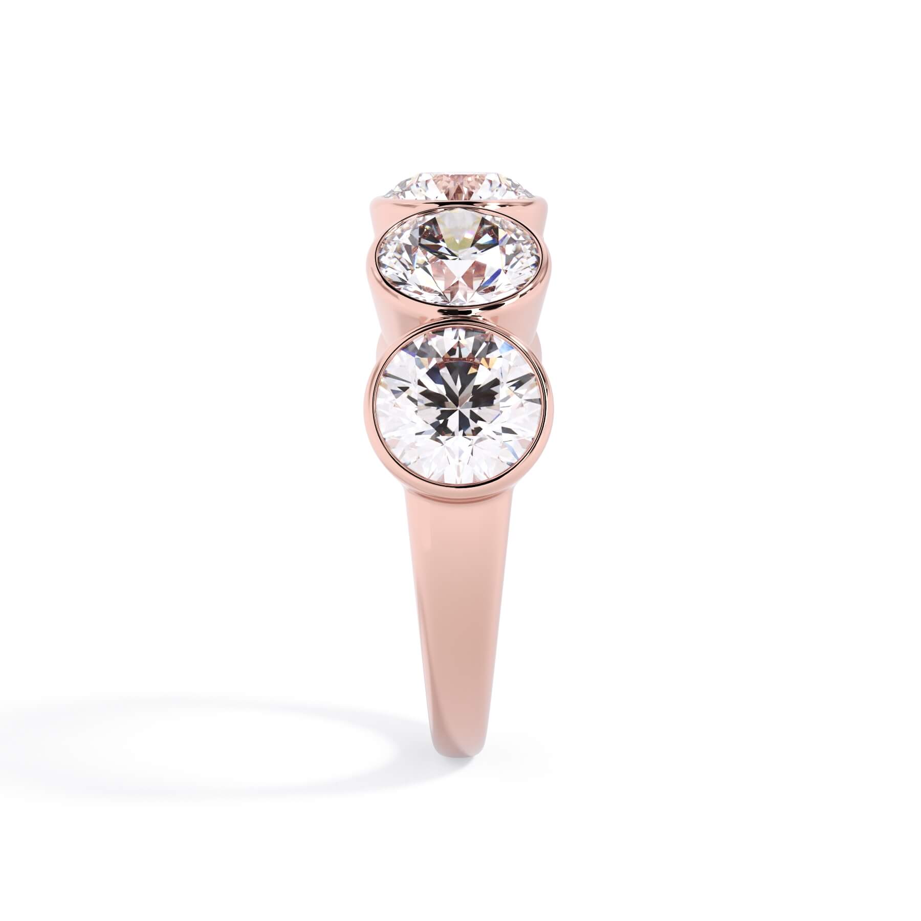 A picture of a five stone diamond wedding ring with round diamonds that are bezel set in rose gold on a white background with a side profile view.