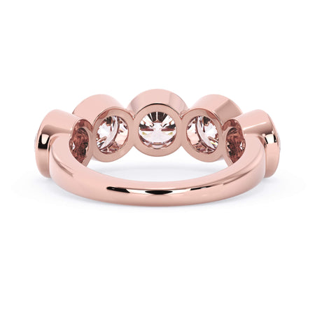 A picture of a five stone diamond wedding ring with round diamonds that are bezel set in rose gold on a white background with a view of the underside of the ring.