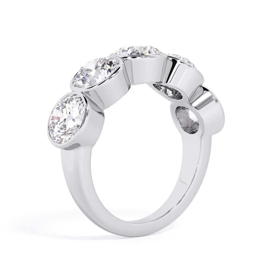 A picture of a five stone diamond wedding ring with round diamonds that are bezel set in white gold or platinum on a white background with a slightly angled, through the finger view.