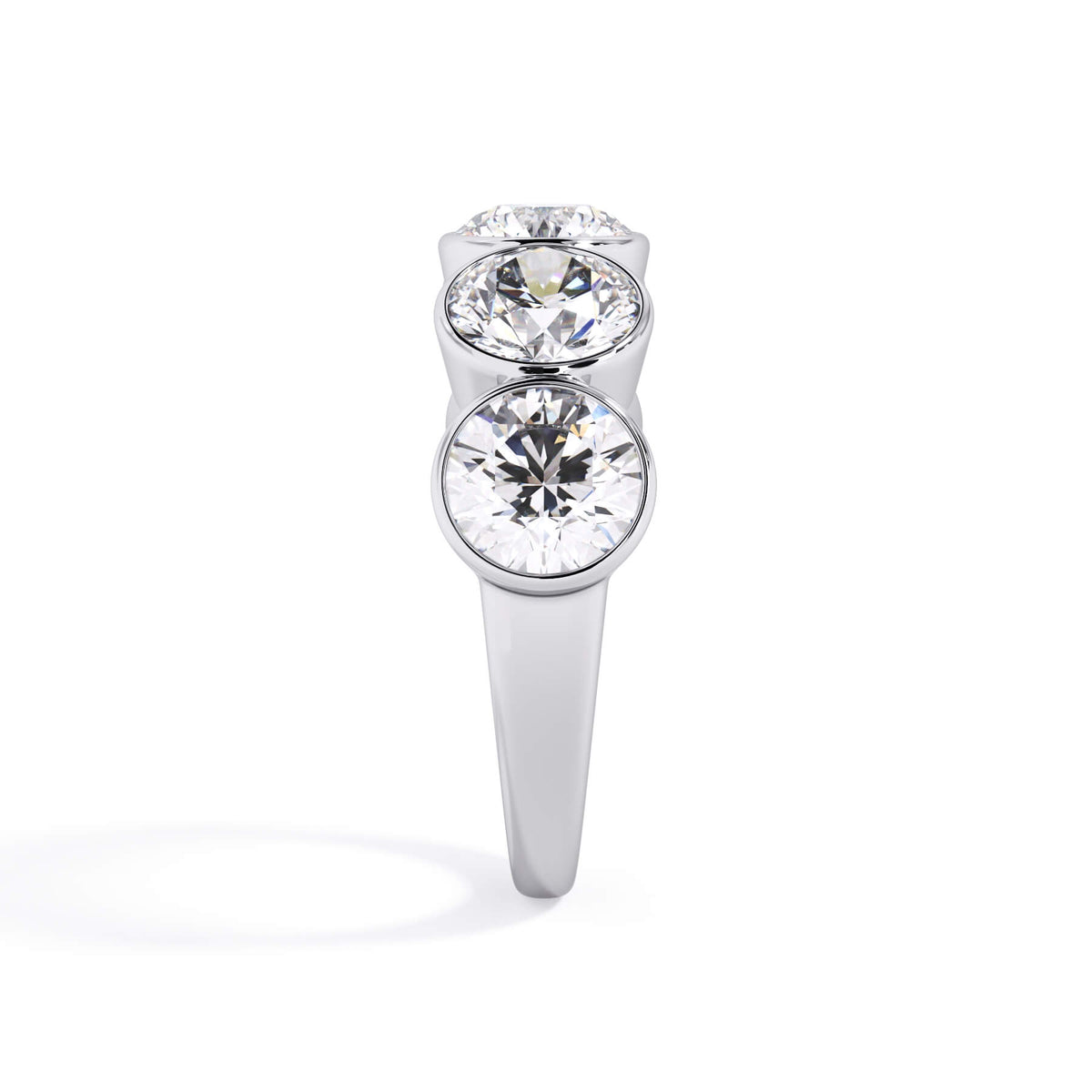 A picture of a five stone diamond wedding ring with round diamonds that are bezel set in white gold or platinum on a white background with a side profile view.