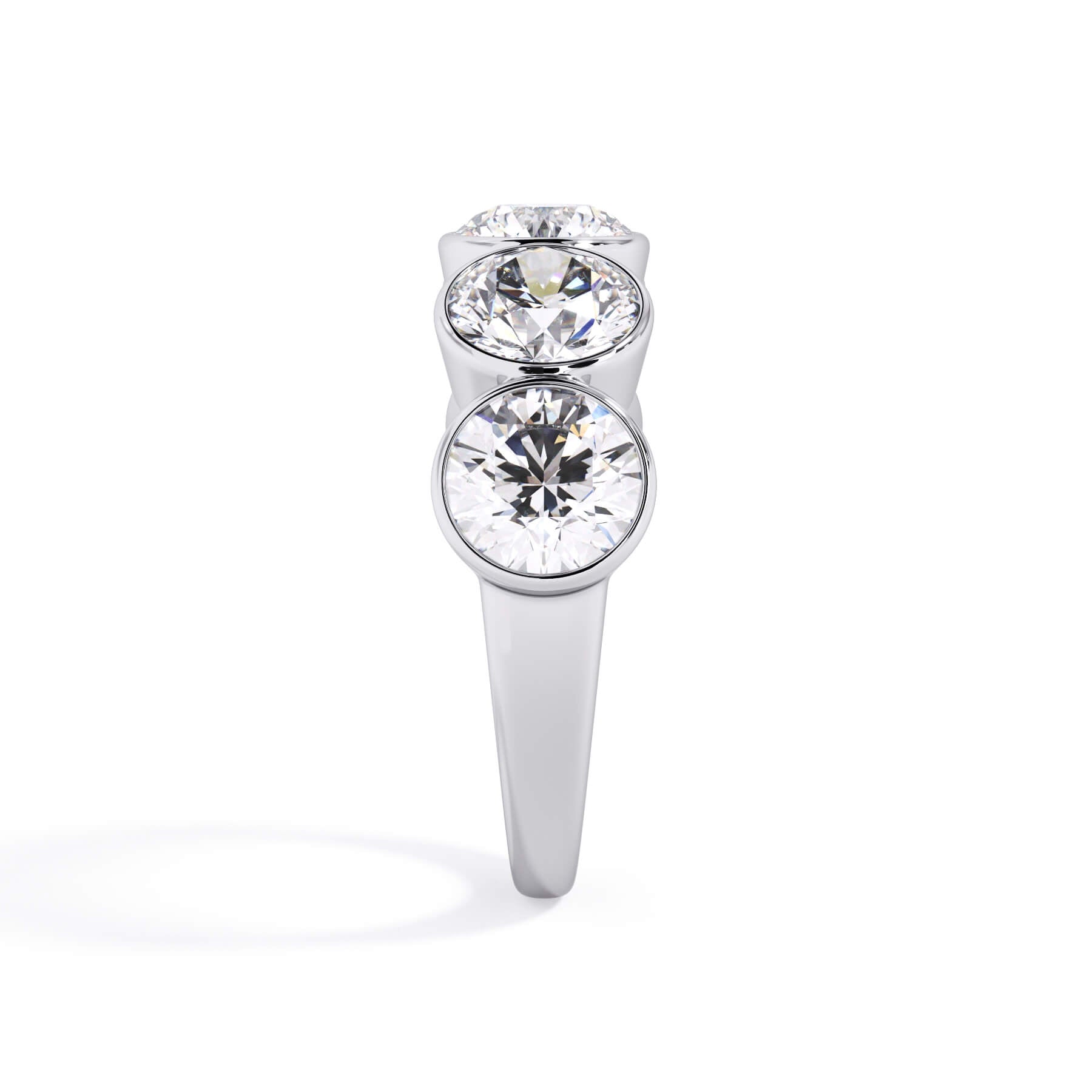 A picture of a five stone diamond wedding ring with round diamonds that are bezel set in white gold or platinum on a white background with a side profile view.