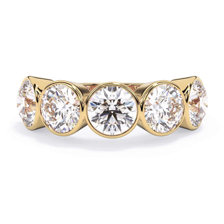 A picture of a five stone diamond wedding ring with round diamonds that are bezel set in yellow gold on a white background with the ring facing forward, lying down.