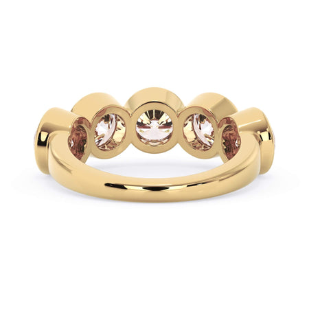 A picture of a five stone diamond wedding ring with round diamonds that are bezel set in yellow gold on a white background with a view of the underside of the ring.
