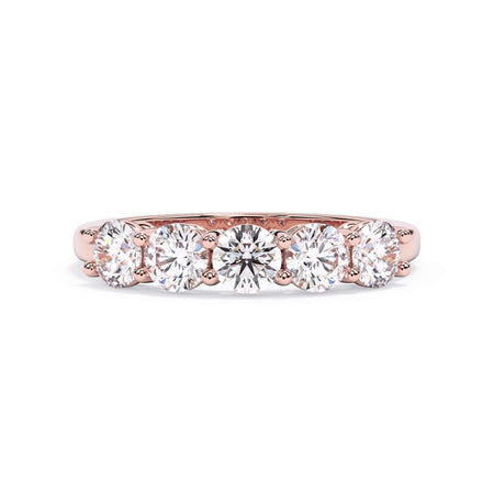A picture of a five stone diamond wedding ring with round diamonds that are shared prong set in rose gold on a white background with the ring facing forward, lying down.