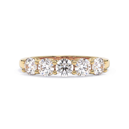 A picture of a five stone diamond wedding ring with round diamonds that are shared prong set in yellow gold on a white background with the ring facing forward, lying down.