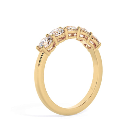 A picture of a five stone diamond wedding ring with round diamonds that are shared prong set in yellow gold on a white background with a slightly angled, through the finger view.