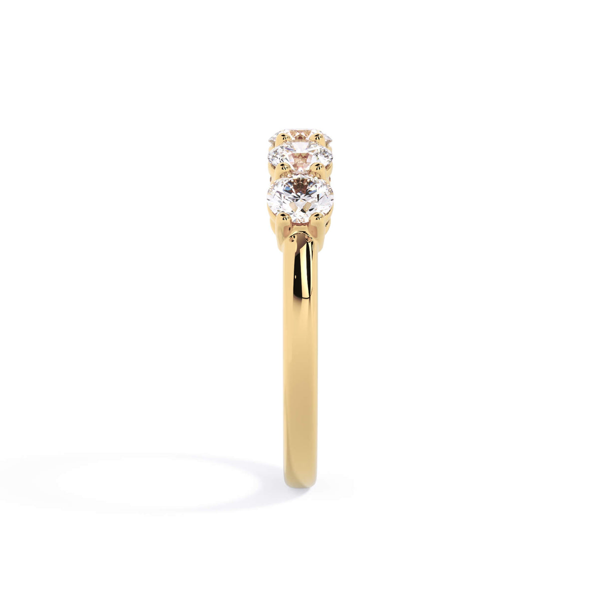 A picture of a five stone diamond wedding ring with round diamonds that are shared prong set in yellow gold on a white background with a side profile view.